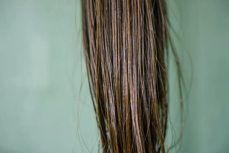 Close-up de fios de cabelo brilhante e saudável caindo sobre um fundo suave.