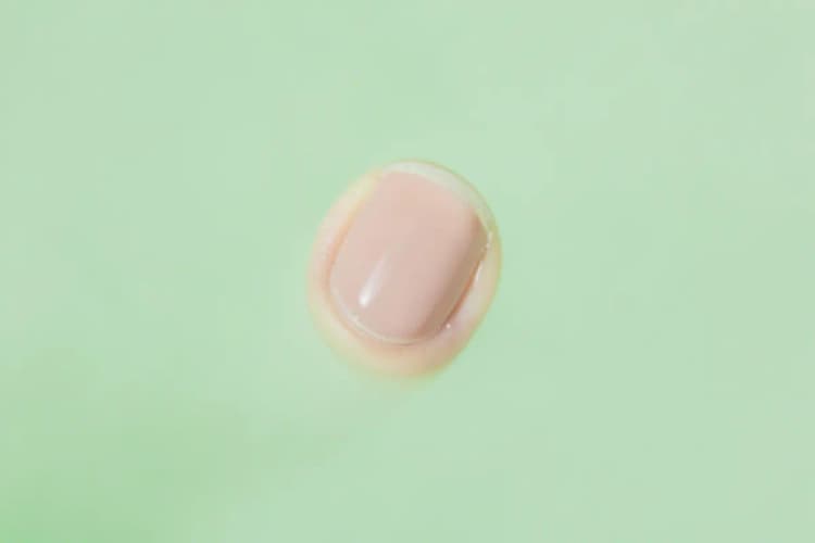 Unhas fortes e bem cuidadas com esmalte nude, em close-up.