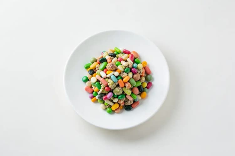 Um close-up de um prato de comida com vitaminas e minerais representados por pequenos objetos coloridos.