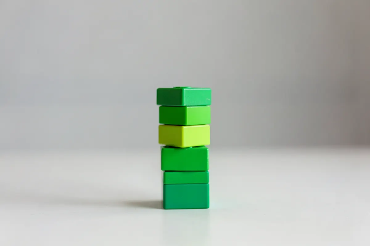 Uma pessoa organizando blocos de construção coloridos em uma mesa, formando uma torre.