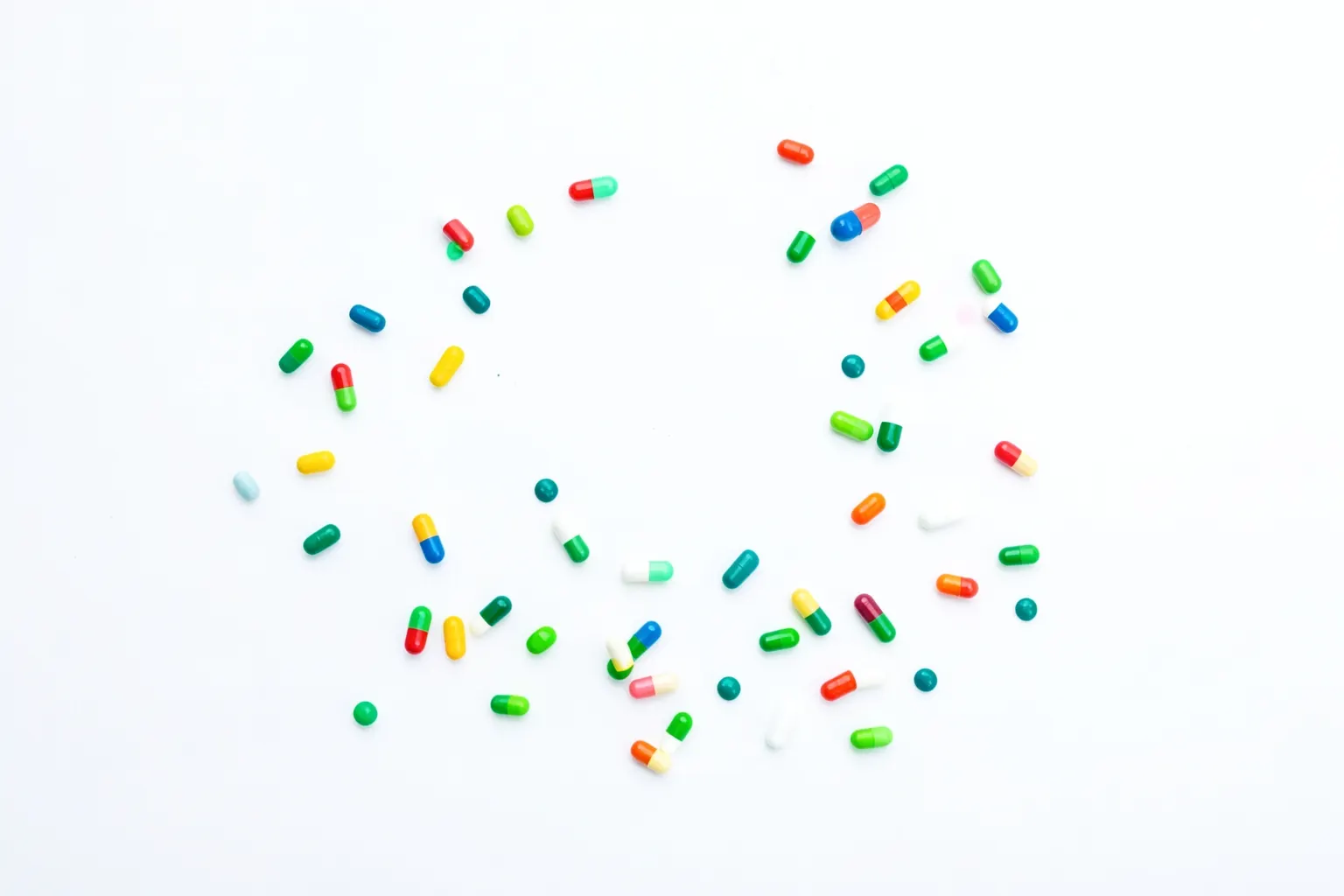 Uma colagem de pílulas e cápsulas de vitaminas coloridas sobre um fundo branco e limpo.
