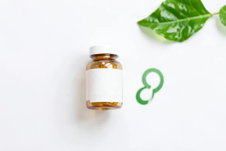 Um frasco de ômega 3 ao lado de um símbolo de gravidez em um fundo branco com uma folha verde desfocada