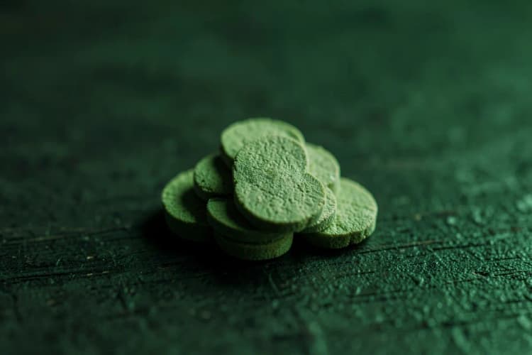 Uma pilha de comprimidos de Ginkgo Biloba sobre uma superfície de madeira escura.