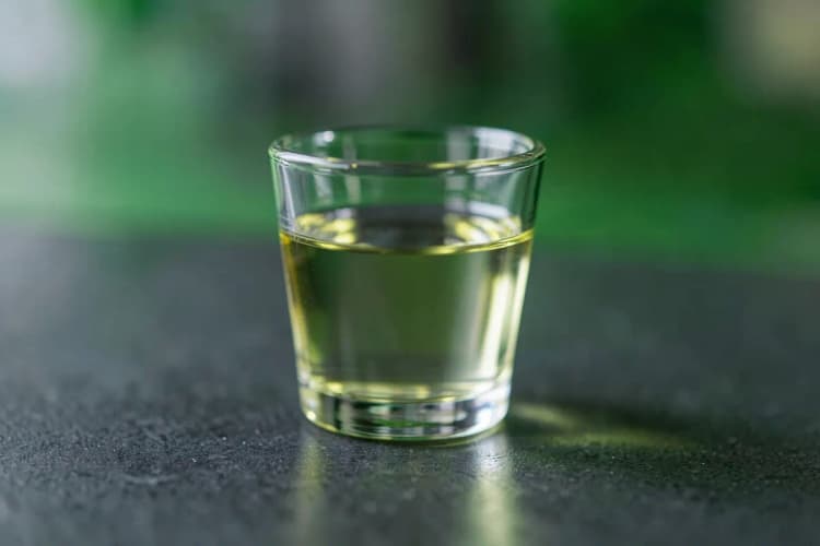 Um copo de shot com óleo de coco líquido transparente.