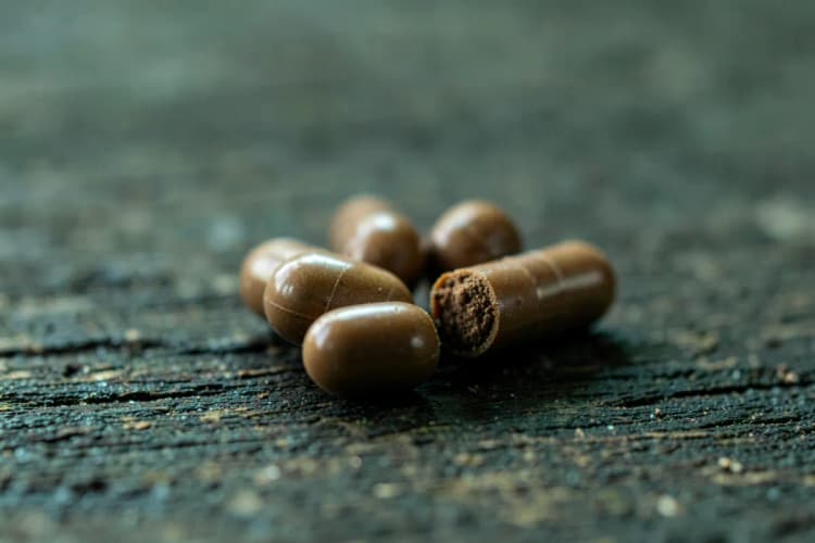 Cápsulas de maca peruana em close-up extremo sobre uma superfície de madeira rústica.
