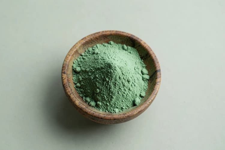 Um monte de pó de maca peruana em uma tigela de madeira rústica.