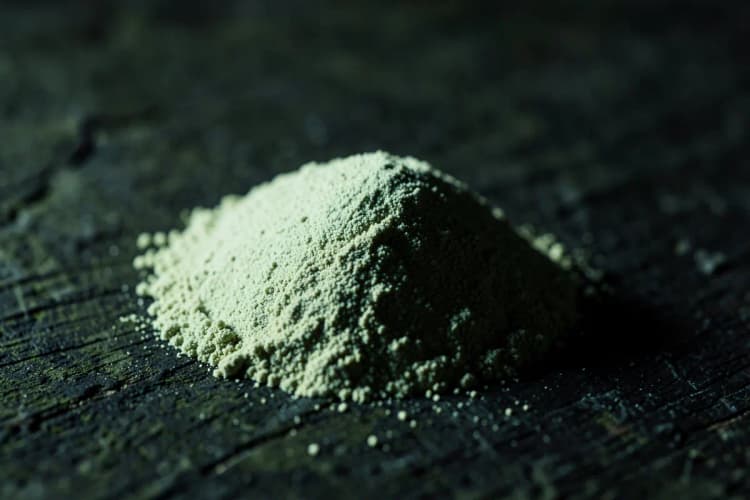 Um monte de maca peruana em pó em uma superfície escura.
