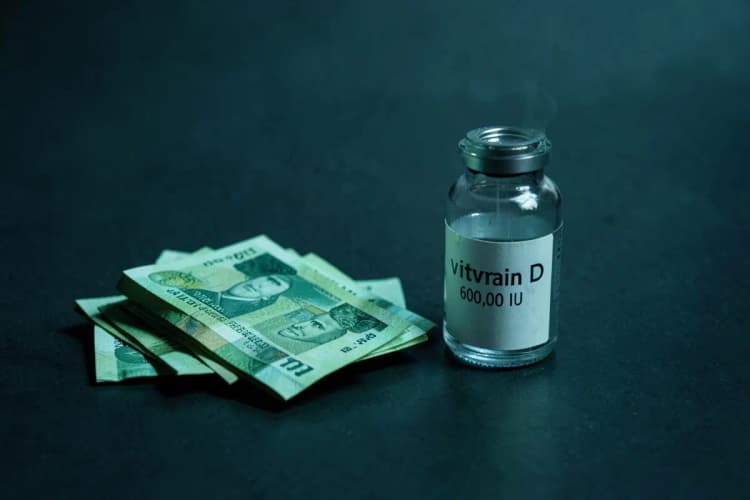 Notas de dinheiro e frasco de vitamina D 600.000 UI.